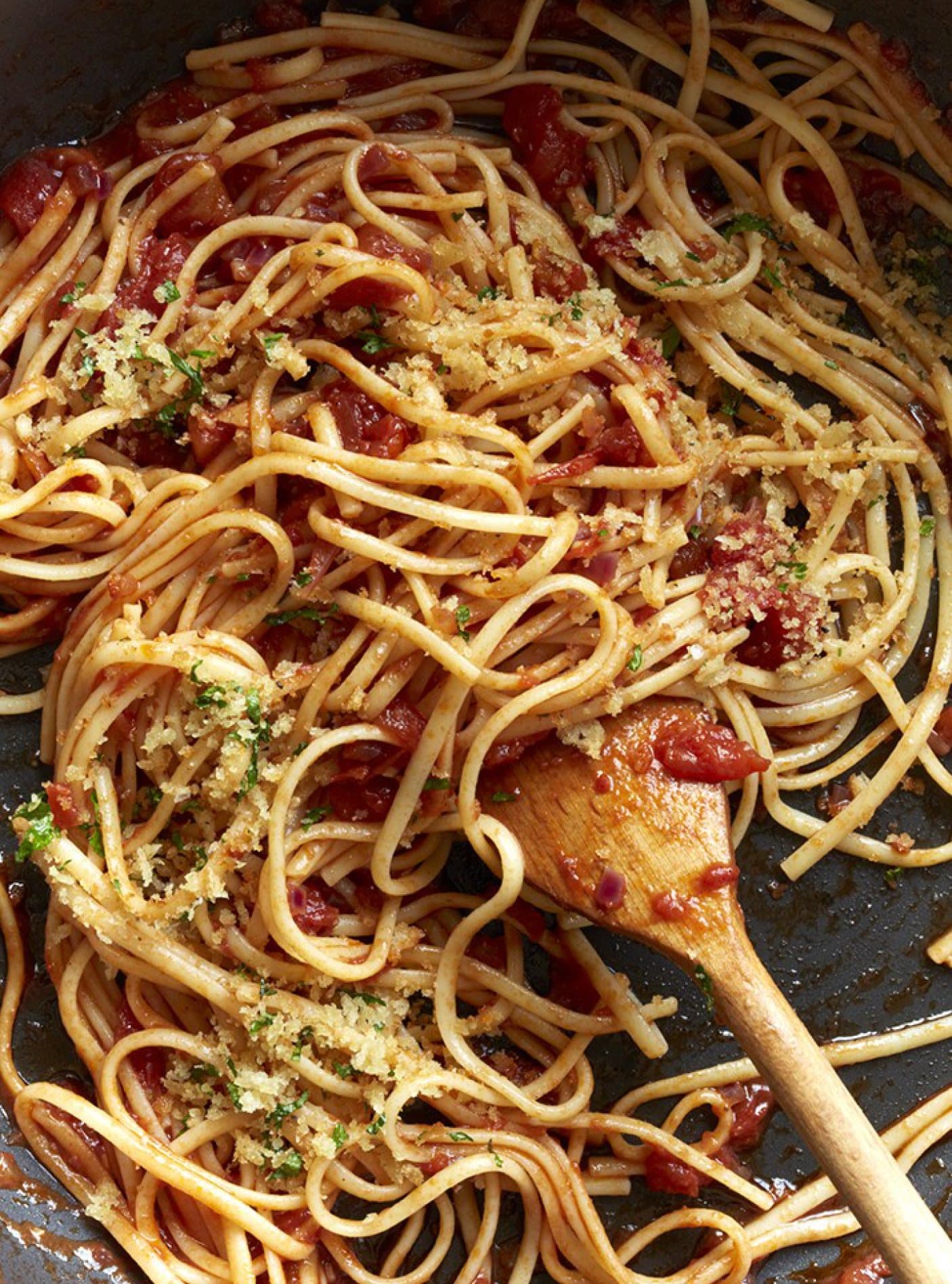 Close-up of spaghetti in tomato sauce with a wooden spoon