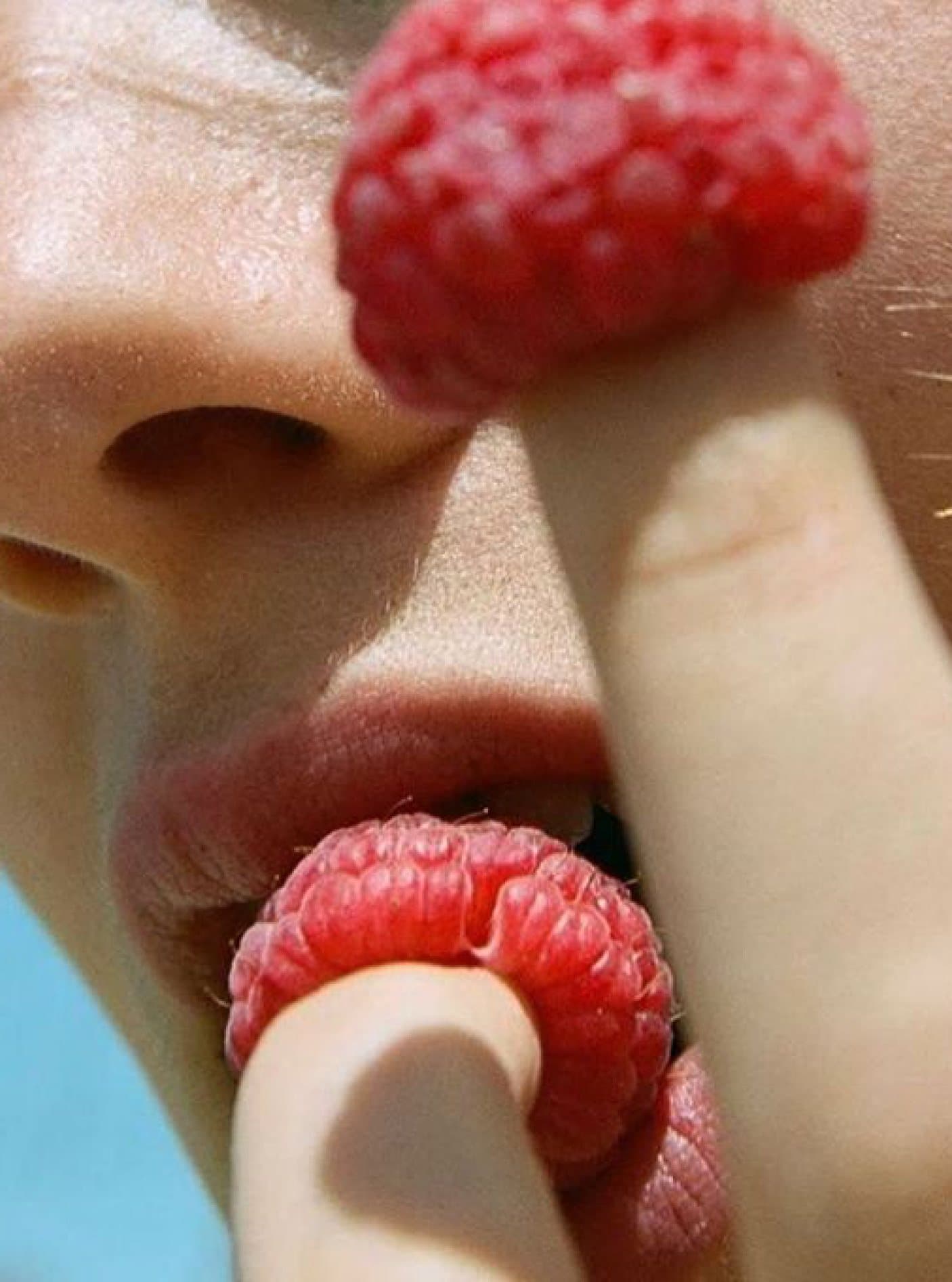Close-up of a person tasting a fresh raspberry