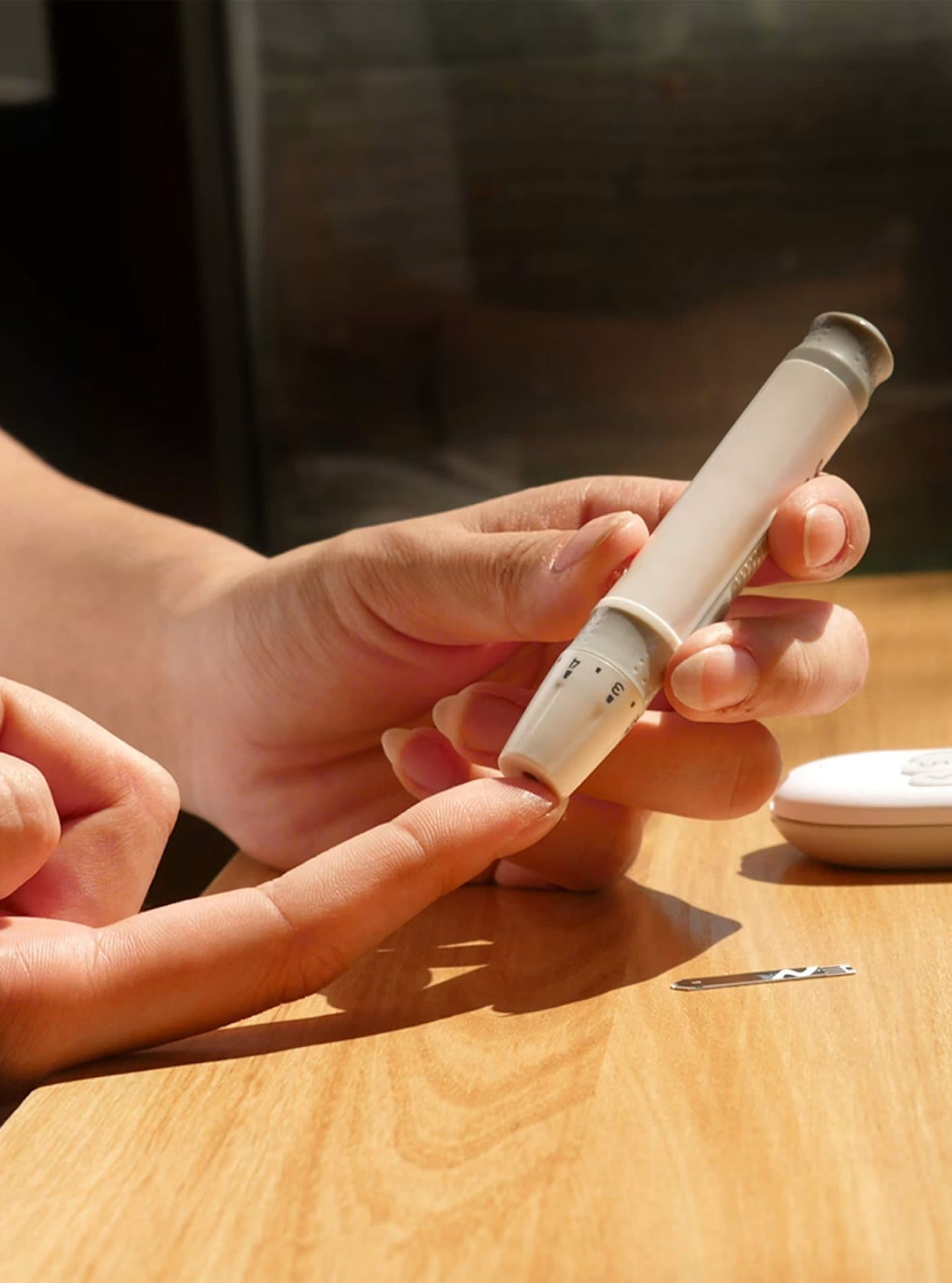 Hands holding an insulin pen over a wooden table